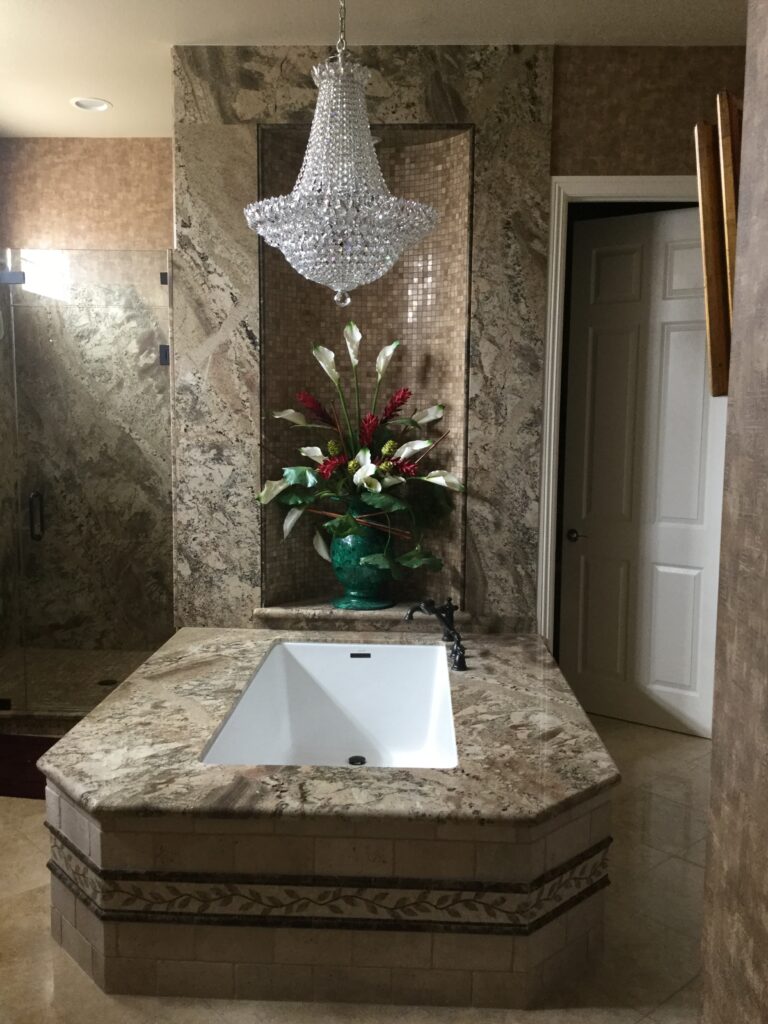 A bathtub with a chandelier over it.